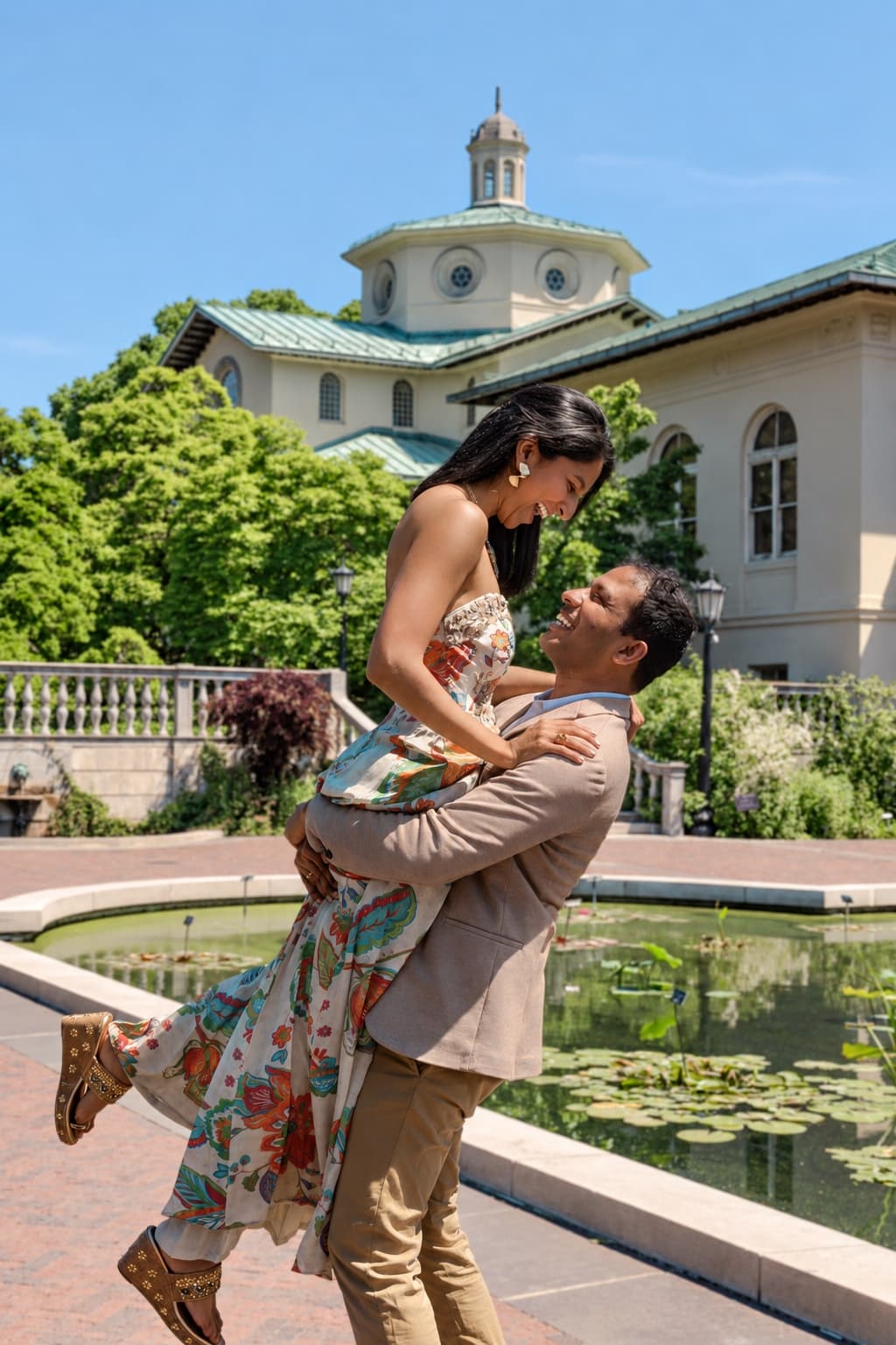 Sameer lifting Neha as they laugh together in a garden