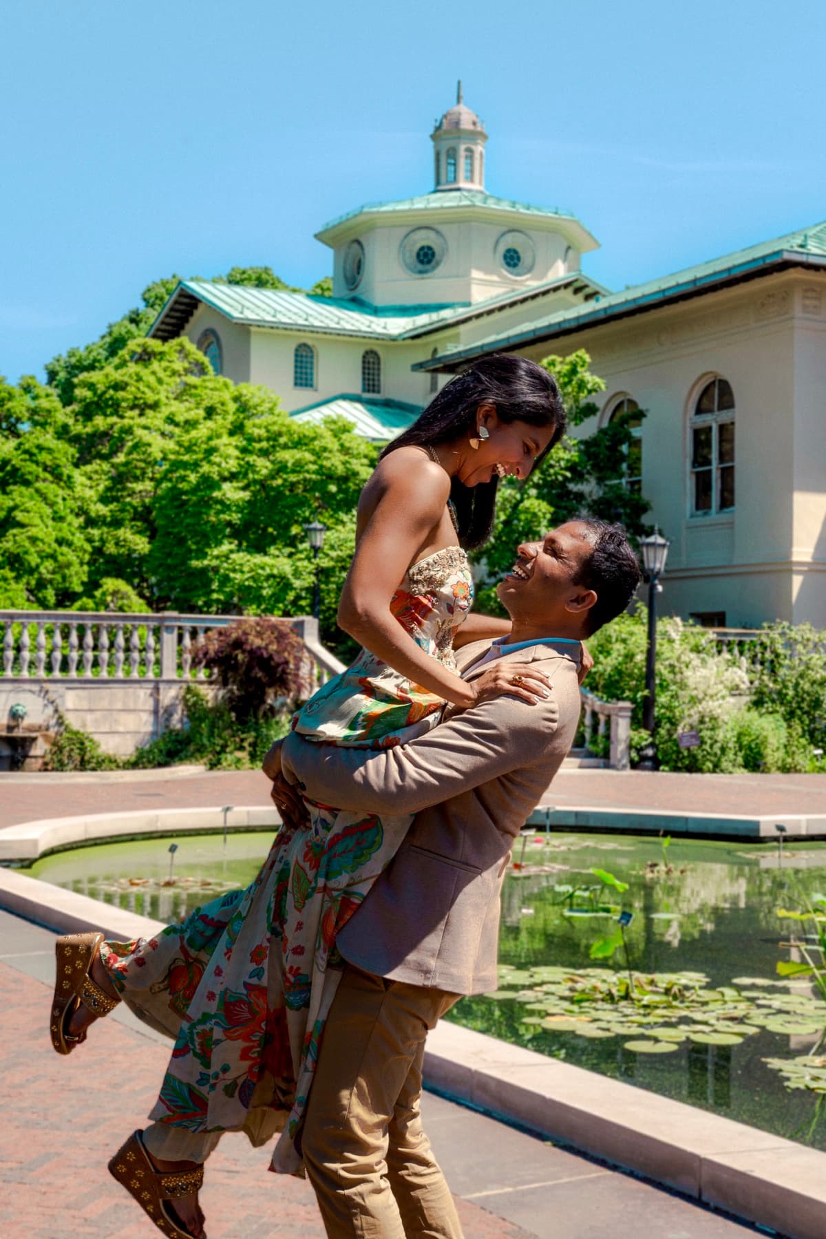 Sameer lifting Neha as they laugh together in a garden